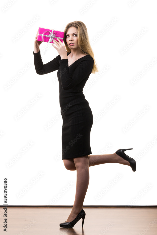 Girl holding present shaking pink gift box Girl holding present shaking pink gift box