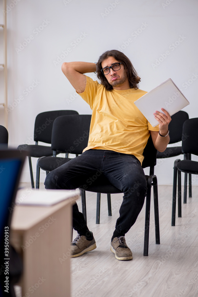 Young male student waiting for teacher in the classroom Young male student waiting for teacher in the classroom