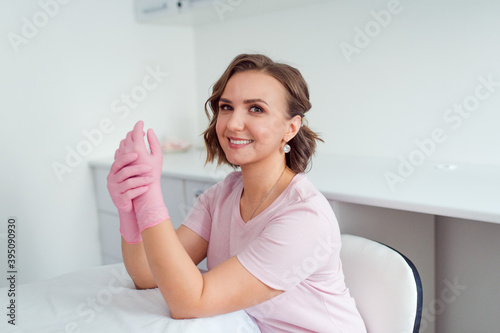 Photography beautiful woman cosmetologist or beauty salon specialist in rubber gloves sittin