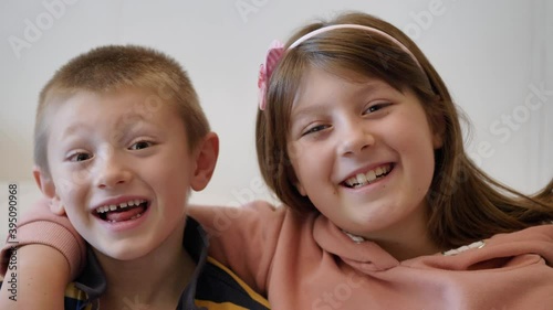 brother and sister are smiling and laughing together at home