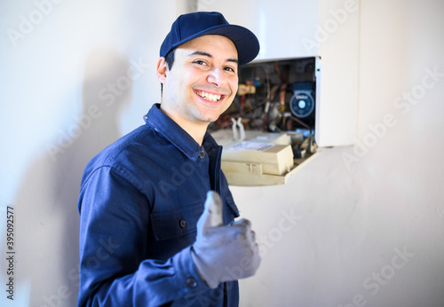 Smiling technician repairing an hot-water heater and showing thumbs up