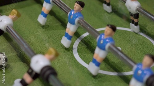 plastic toy players playing in foosball on entertainment tabletop with green football field top view photo