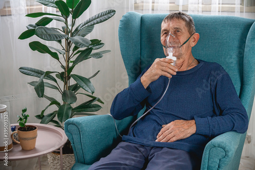 Photography elderly senior sits in a armchair with an oxygen mask in quarantine at home