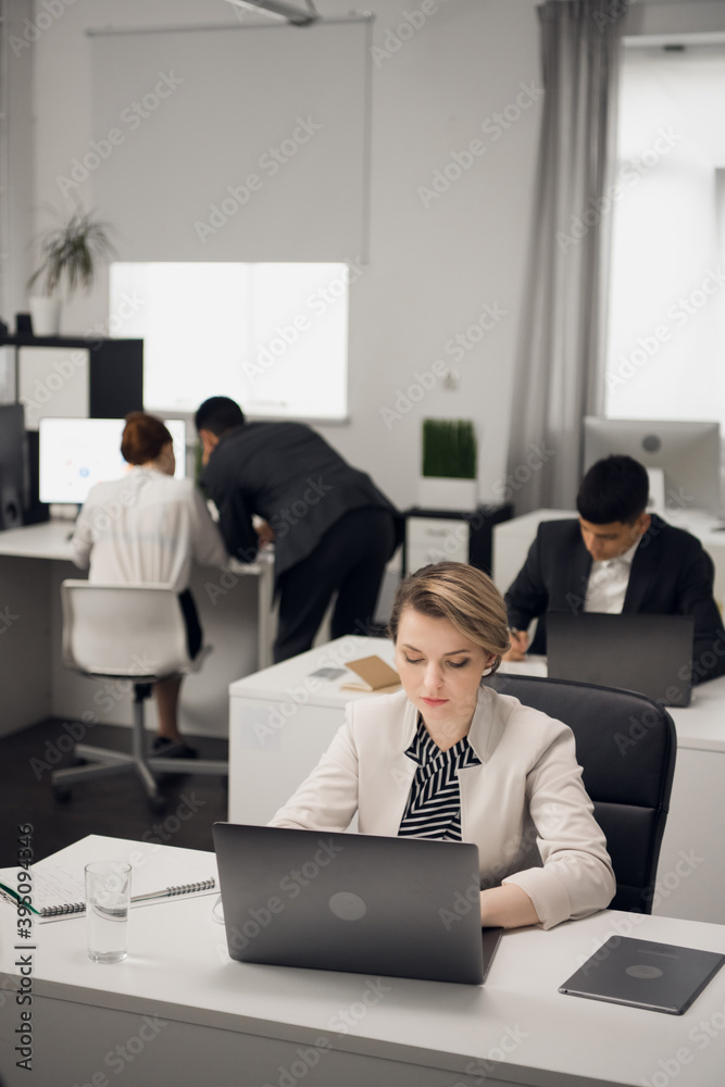 Two bookshop managers working on laptop in a large bright office. Business dress code Two bookshop managers working on laptop in a large bright office. Business dress code