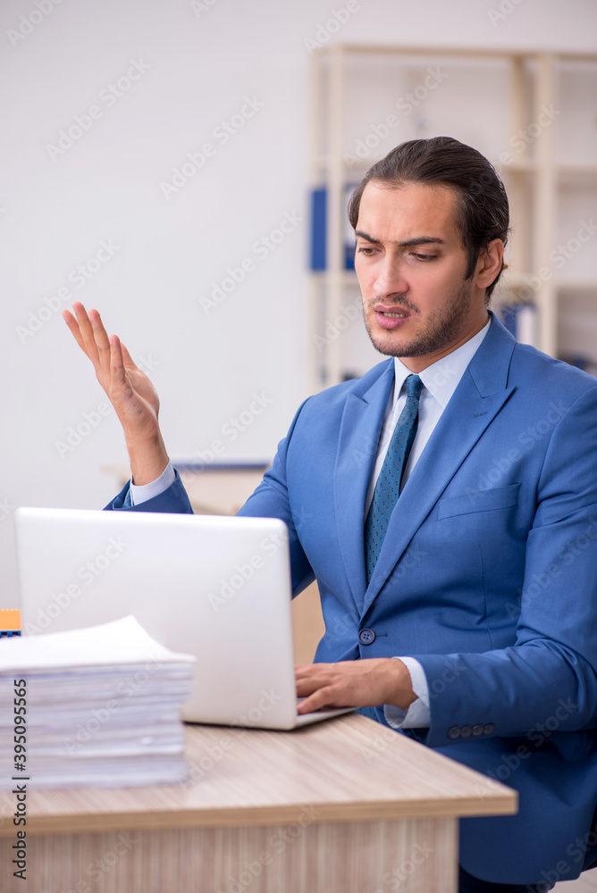 Young male employee and too much work in the office Young male employee and too much work in the office