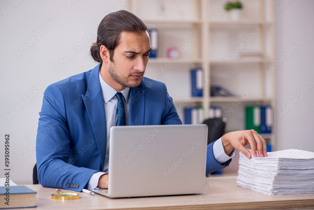 Young male employee and too much work in the office Young male employee and too much work in the office