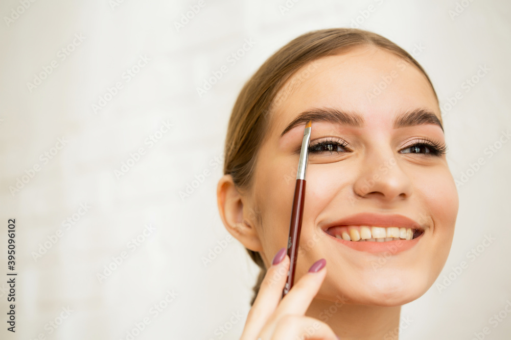 A beautiful girl with natural fresh makeup, healthy skin holds a brush near her face. Makeup, skin care concept