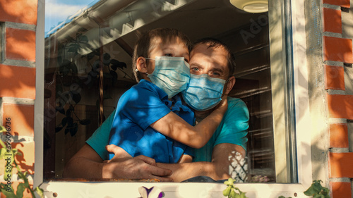 Father and Son in Medical Masks Hugs Near Window at Home. Family Concept on Quarantine as Illness Prevention. Medical Concept of Healthy, Safety Life, Coronavirus, Virus protection, Stay at Home  