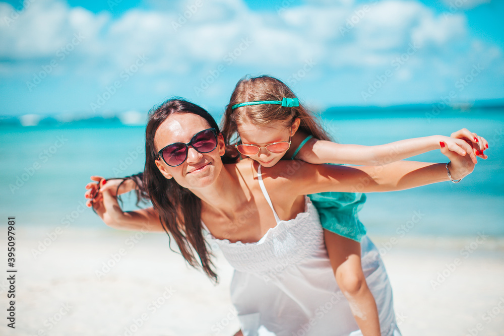 Beautiful mother and daughter at the beach enjoying summer vacation Beautiful mother and daughter at the beach enjoying summer vacation