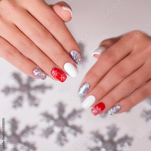 Close up view of beautiful female hand with creative manicure nails  red and silver gel polish  winter design