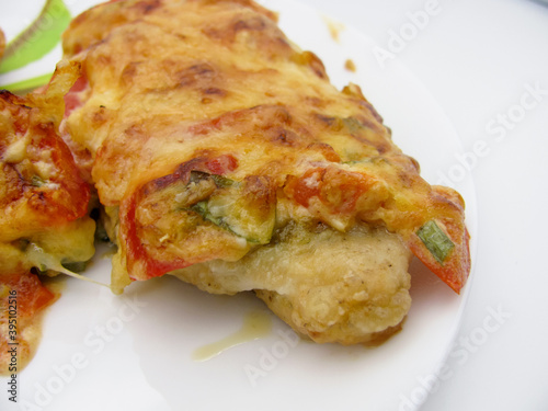 Chicken fillet baked in the oven under a cheese coat with tomatoes, sweet pepper, mayonnaise and mustard.