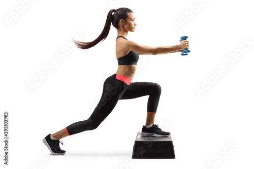 Fototapeta Naklejka Na Ścianę i Meble -  Full length profile shot of a young female exercising on a stepper with small weights