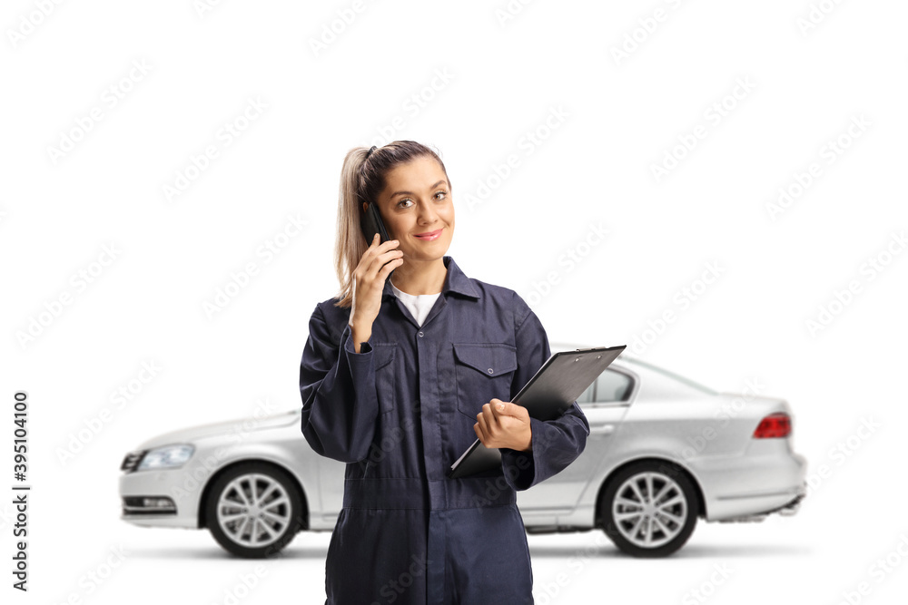 Silver car and a female auto mechanic talking on a mobile phone Silver car and a female auto mechanic talking on a mobile phone