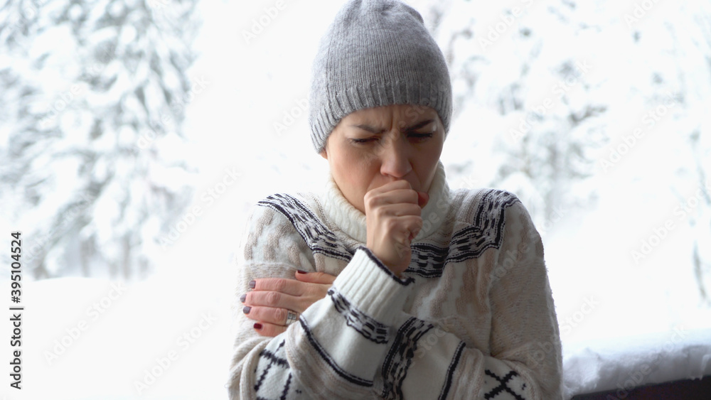 Fototapeta premium Young woman coughing outdoors in winter scenery 