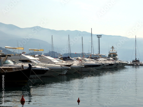 Row of white s motor on the dock at the pier in Budva Montenegro. Silhouettes of mountains in the background in the haze photo