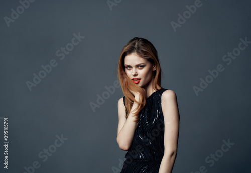 A beautiful lady in an evening dress on a gray background gestures with her hands Copy Space Model