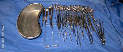 Instrumental quirúrgico sobre tela azul con bandeja de metal y tijeras de cirujano