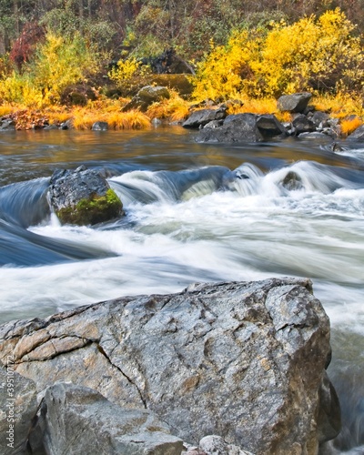 Autumn colors line the bank as the Trinity River rushes past large boulders.