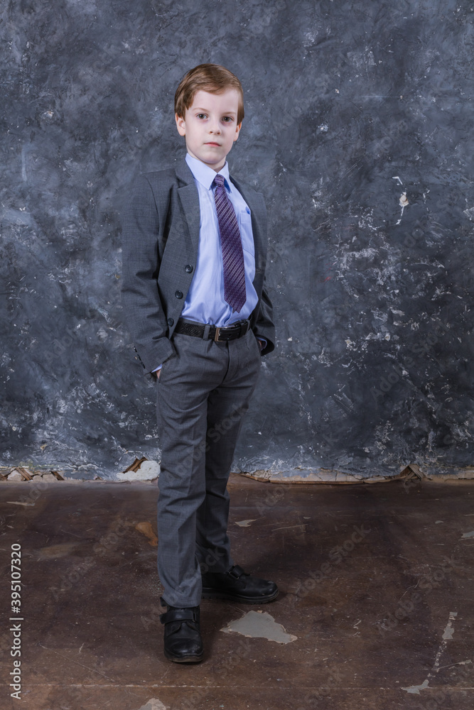 Cute schoolboy dressed in suit studio portrait.
