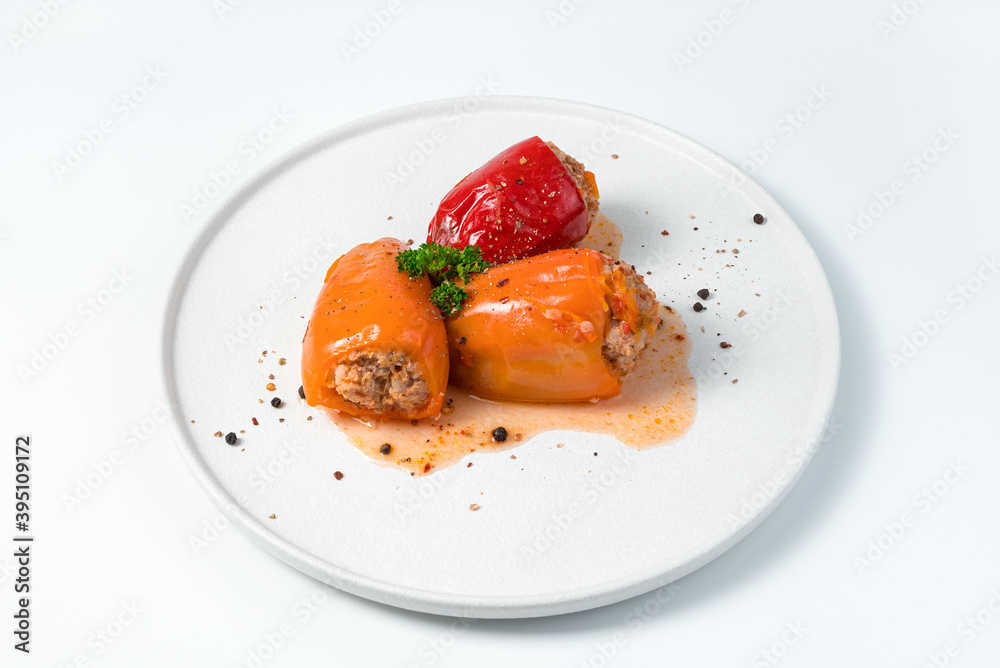 Three red and orange Bulgarian peppercorns with meat on a white plate. Culinary background, side view. The concept of cooking. Three red and orange Bulgarian peppercorns with meat on a white plate. Culinary background, side view. The concept of cooking.