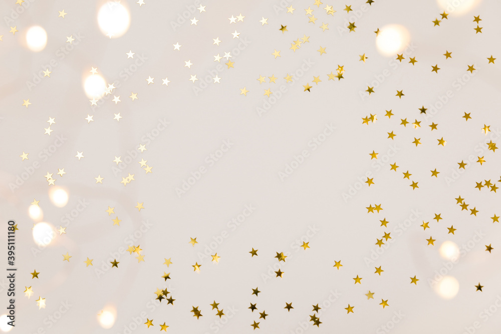 Festive gold background. Shining stars confetti and fairy lights on beige and Set Sail Champagne background. Christmas. Wedding. Birthday. Flat lay, top view, copy space Festive gold background. Shining stars confetti and fairy lights on beige and Set Sail Champagne background. Christmas. Wedding. Birthday. Flat lay, top view, copy space