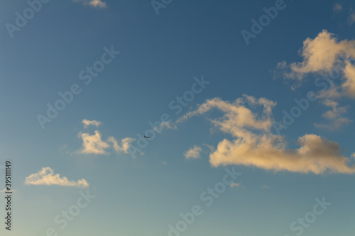 Striking fluffy clouds in the blue sky. Background for designers. Plane in the sky