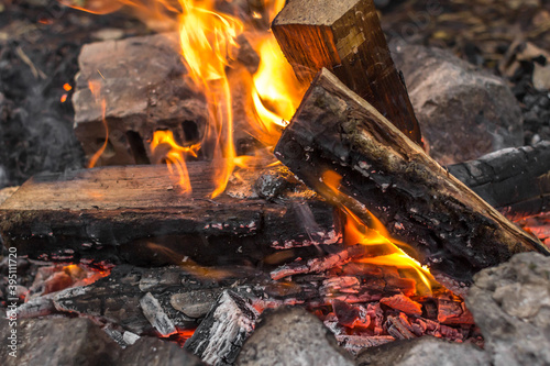 Bright flames. Fire sparks. Burning firewood. Crackling logs on fire. Smouldering coals. Christmas background. The heat and warmth of an open fire. Risk of fire. Dangerous behavior with fire.