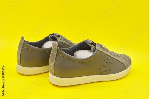 New men's leather gray sneakers on yellow background, top view