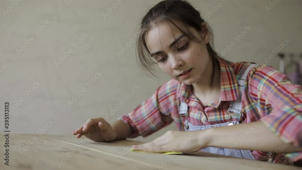Slow motion of craftswoman polishing wooden table with sandpaper while being busy in woodwork workshop Slow motion of craftswoman polishing wooden table with sandpaper while being busy in woodwork workshop