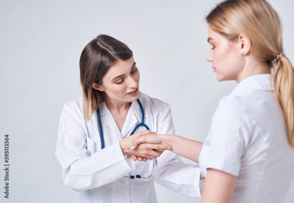 Happy woman doctor in medical gown with stethoscope and patient back view Happy woman doctor in medical gown with stethoscope and patient back view