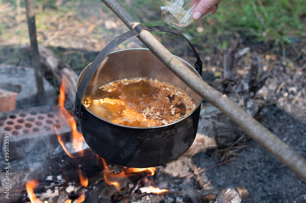 Cooking soup over the fire. Cooking at the stake in a cauldron. Adding spices to the dish. Cooking soup over the fire. Cooking at the stake in a cauldron. Adding spices to the dish.