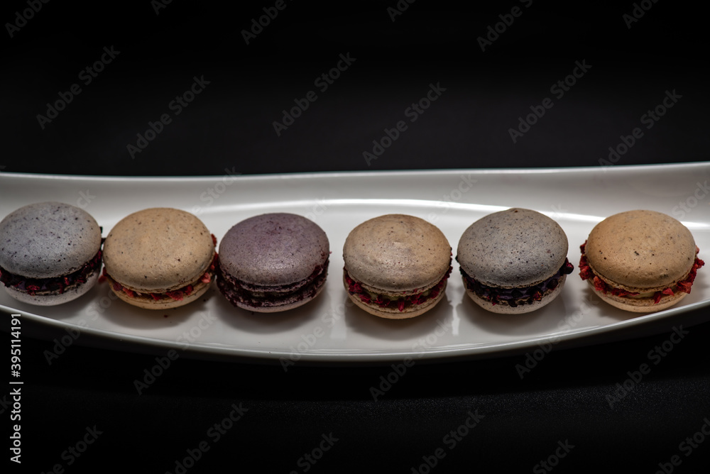 Set of delicious macaroons expensive candies on the black background Set of delicious macaroons expensive candies on the black background