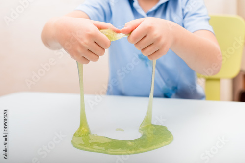  a slime in the hands of a child sitting at a table photo