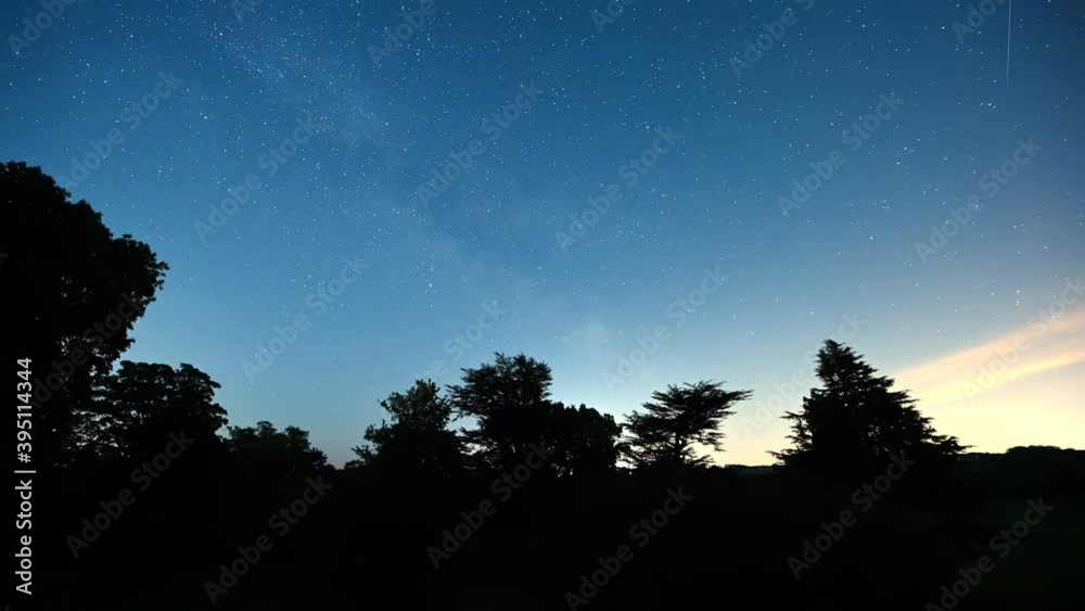 Timelapse of a push through a silhouette window to reveal stars in a clear night sky and dark trees in the foreground