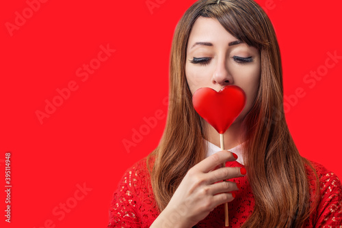 Beautiful girl with long hair with sweets on a red background for Valentine's day