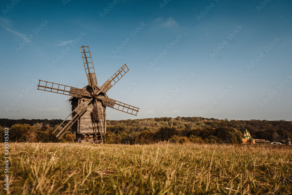 old wooden windmills stand in a field near the forest 1