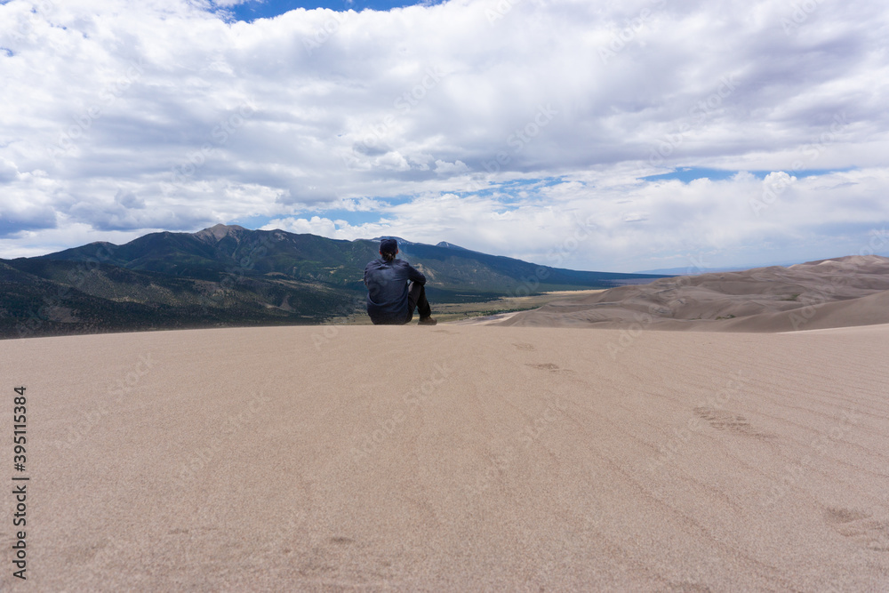 Man sits on top of mountains at Great National Sand Dunes