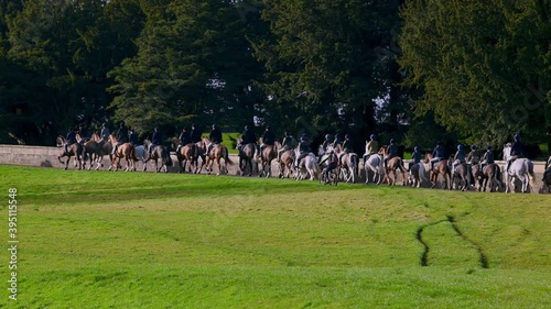 Horse riding fox hunters set off through Capability Brown designed parkland at the beginning of a fox hunt photo