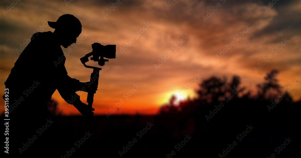 Time lapse: Silhouette of videographer is filming with cinema gimbal video dslr at sunset , professional video, videographer in events. Cinema lens on gimbal. Medium shot from right side