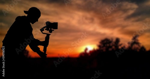 Time lapse: Silhouette of videographer is filming with cinema gimbal video dslr at sunset , professional video, videographer in events. Cinema lens on gimbal. Medium shot from right side