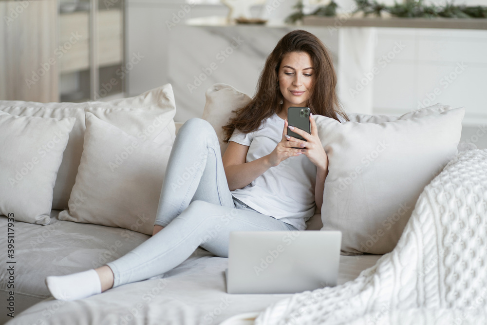 a beautiful brunette woman with a ponytail typing text on her phone is sitting in the living room near a large window. make an application form in the Bank's website app for a loan remotely online a beautiful brunette woman with a ponytail typing text on her phone is sitting in the living room near a large window. make an application form in the Bank's website app for a loan remotely online