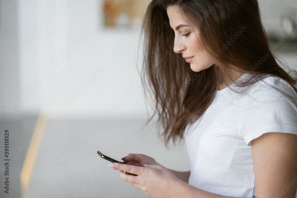 the student Manager prints a message and writes a work on distance learning in the phone. place to copy. A young woman is sitting at home in the kitchen in front of a gadget, looking at the monitor. the student Manager prints a message and writes a work on distance learning in the phone. place to copy. A young woman is sitting at home in the kitchen in front of a gadget, looking at the monitor.