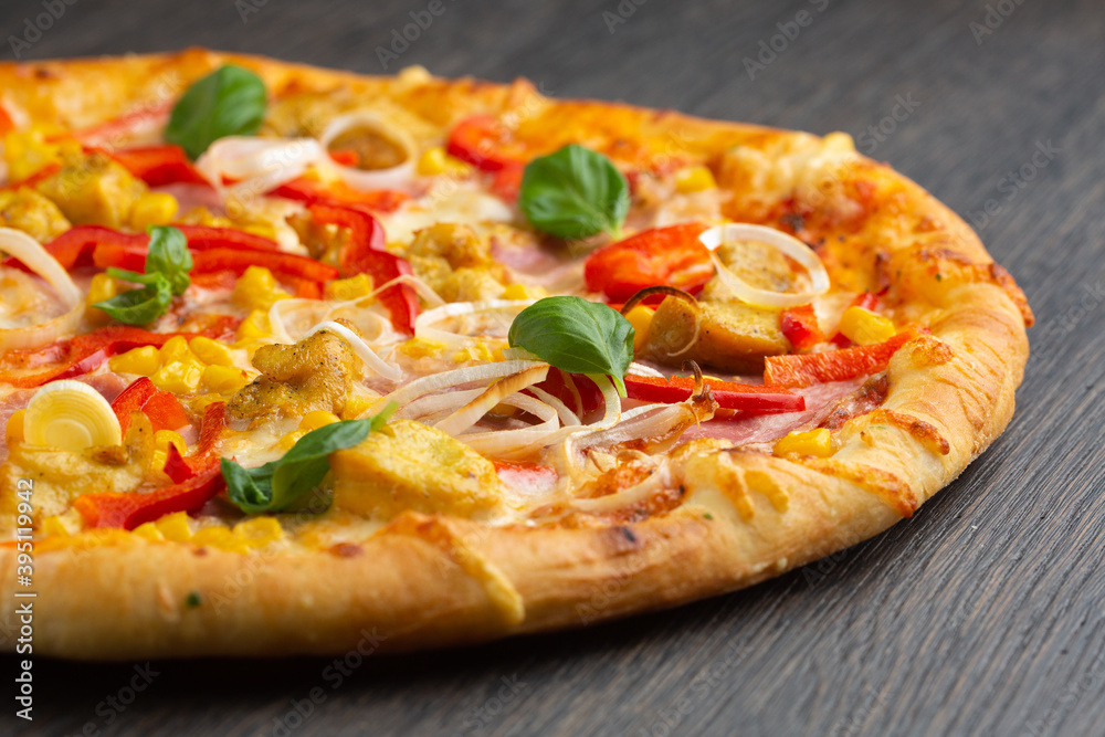 Italian pizza with melted mozzarella cheese, olives and sausage garnished with fresh vegetables and basil leaves Italian pizza with melted mozzarella cheese, olives and sausage garnished with fresh vegetables and basil leaves