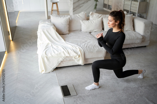 does complex exercises body stretching squats posture fitness gymnastics aerobics. a strong athletic brunette woman communicates via a laptop computer with a coach online in a social network.