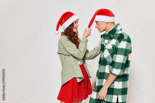 man and woman in santa hat look at each other gray background