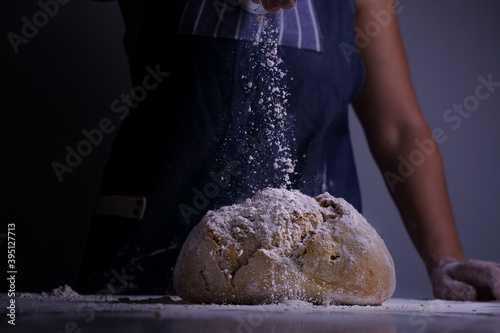 Woman spreading flour over a big bread