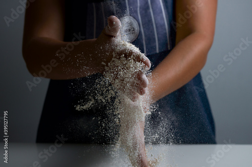 Woman shaking flour in her hands for making bread