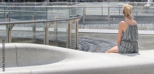 Giovane donna bionda seduta in una piazza moderna a milano photo