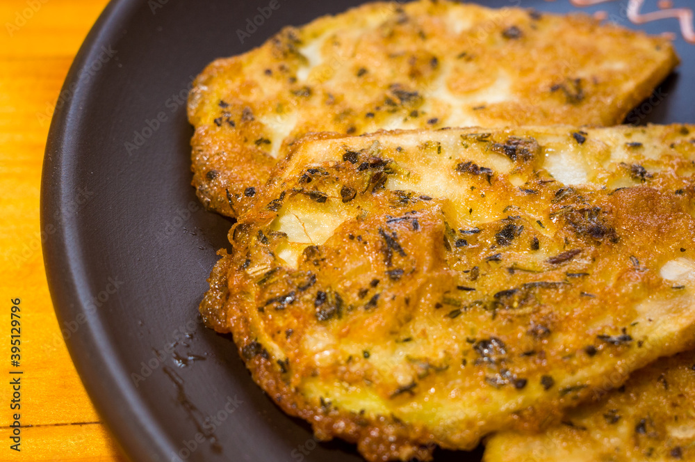 Vegetarian food - celery tuber slices fried in batter in a ceramic plate on a wooden table, close up Vegetarian food - celery tuber slices fried in batter in a ceramic plate on a wooden table, close up