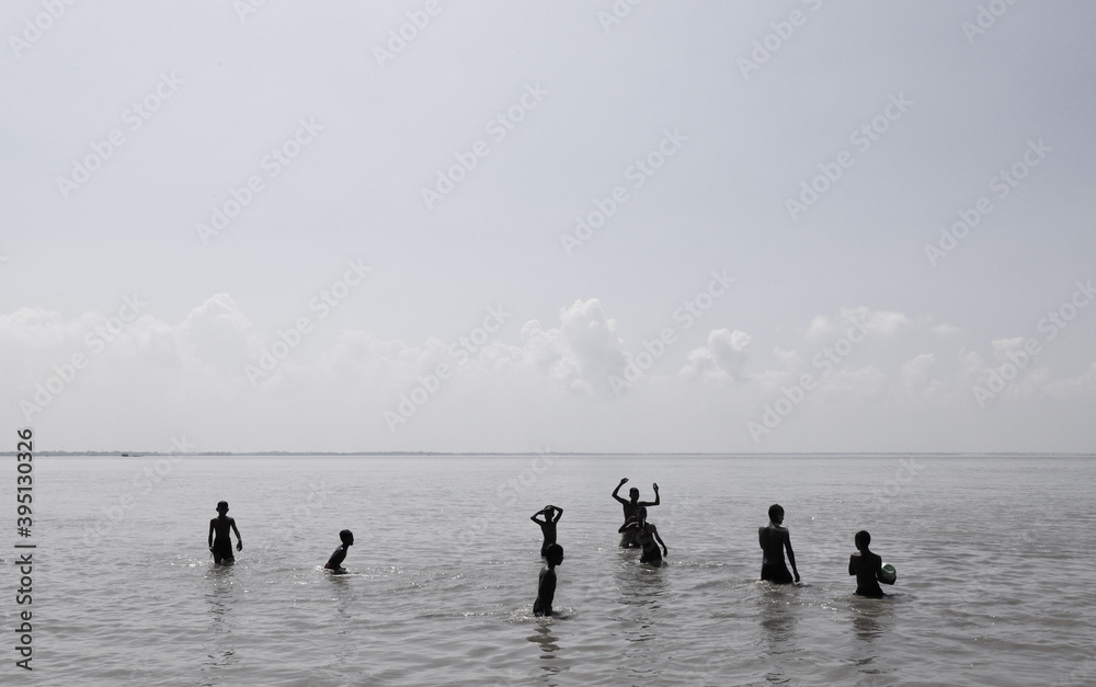 Naklejka premium Local young boys taking a bath ,swimming and playing ball in the Padma river in a hot summer day noon